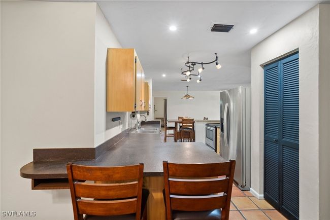 Kitchen with appliances with stainless steel finishes, light tile patterned floors, sink, rail lighting, and kitchen peninsula | Image 12