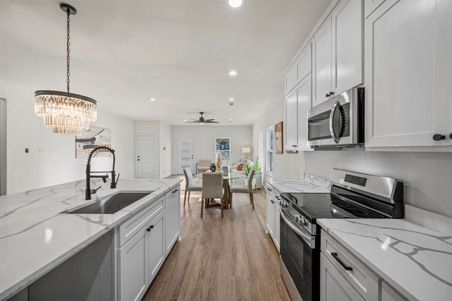 Kitchen with recessed lighting, a sink, stainless steel appliances, pendant lighting, and wood finished floors | Image 11