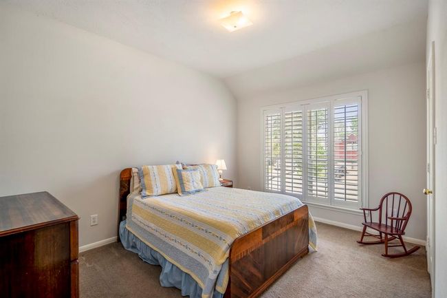 Another upstairs bedroom features plantation shutters on the window, a vaulted ceiling that adds to the spacious feel, and a walk-in closet for convenient storage. | Image 31