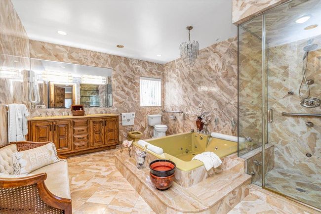 En-suite Bathroom featuring tile walls, separate shower stall, double vanity, toilet, and a whirlpool tub | Image 16