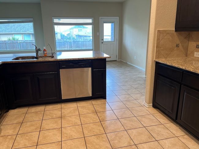Kitchen featuring stainless steel dishwasher, a sink, healthy amount of natural light, and light tile patterned floors | Image 20