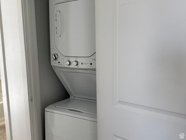 Laundry area featuring stacked washing maching and dryer, carpet floors, and laundry area | Image 8