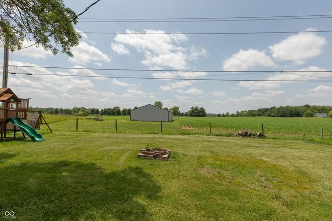view of yard featuring a view of countryside, a playground, and an outdoor fire pit | Image 23