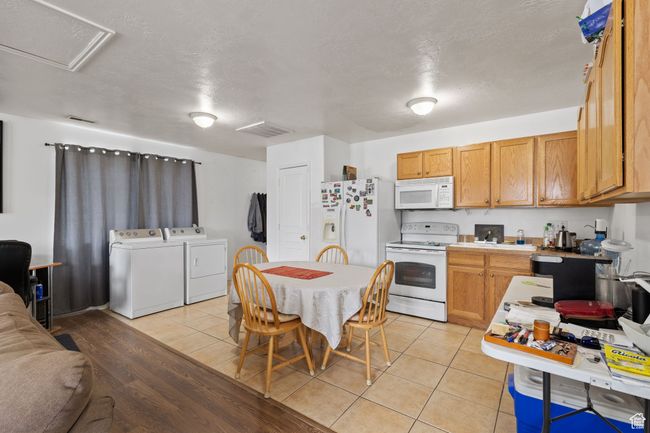 Kitchen with washer and clothes dryer, light tile patterned flooring, visible vents, white appliances, and light countertops | Image 44