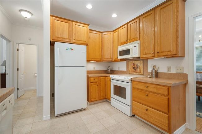 Kitchen featuring light tile patterned floors, light countertops, white appliances, crown molding, and recessed lighting | Image 14