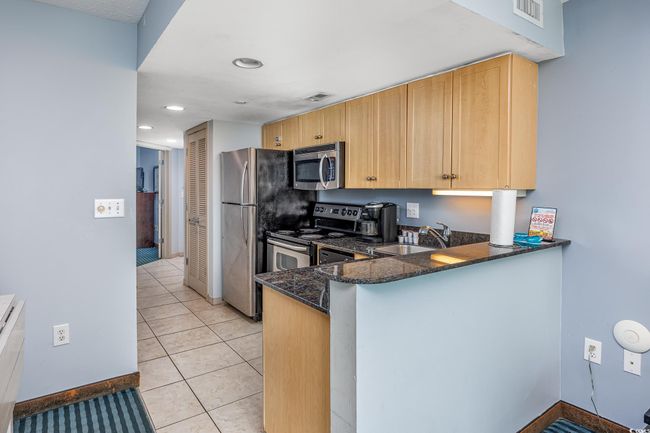 Kitchen featuring dark stone counters, visible vents, stainless steel appliances, and a sink | Image 9