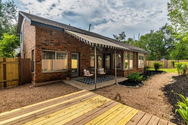 Back of property featuring brick siding, a fenced backyard, a wooden deck, and a patio | Image 33