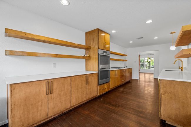Kitchen featuring open shelves, a sink, appliances with stainless steel finishes, dark wood finished floors, and brown cabinetry | Image 14