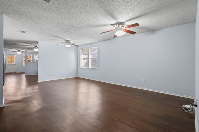 Unfurnished living room featuring dark hardwood / wood-style flooring and a textured ceiling | Image 4