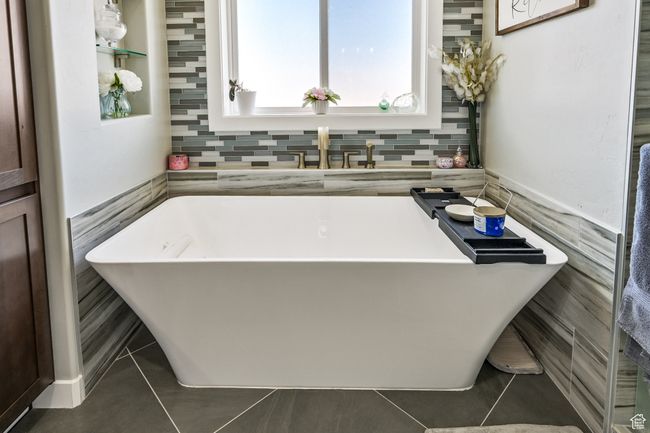 Full bathroom with a soaking tub, tile patterned floors, and tile walls | Image 40