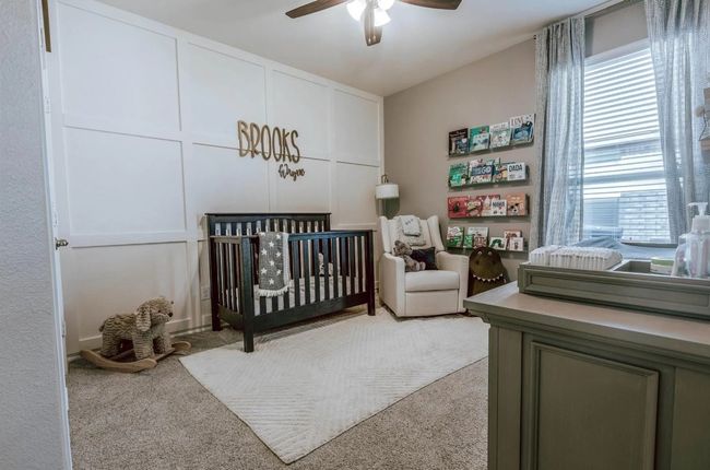 Bedroom featuring light carpet, a nursery area, a ceiling fan, and a decorative wall | Image 9