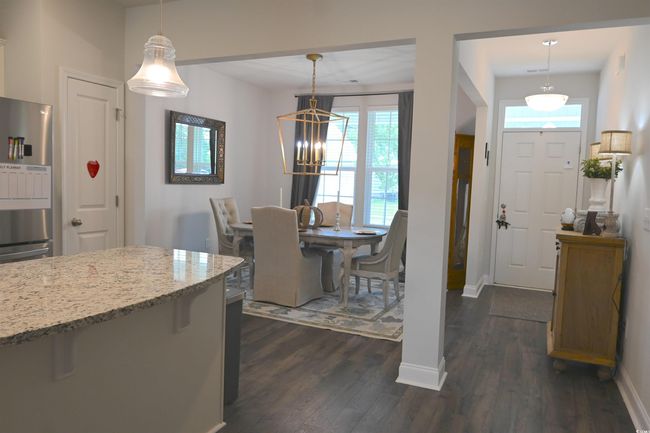 Dining area with dark wood finished floors, plenty of natural light, and a chandelier | Image 9