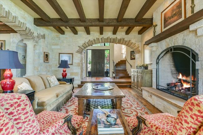 Living room featuring beamed ceiling, a fireplace, wood finished floors, and arched walkways | Image 9