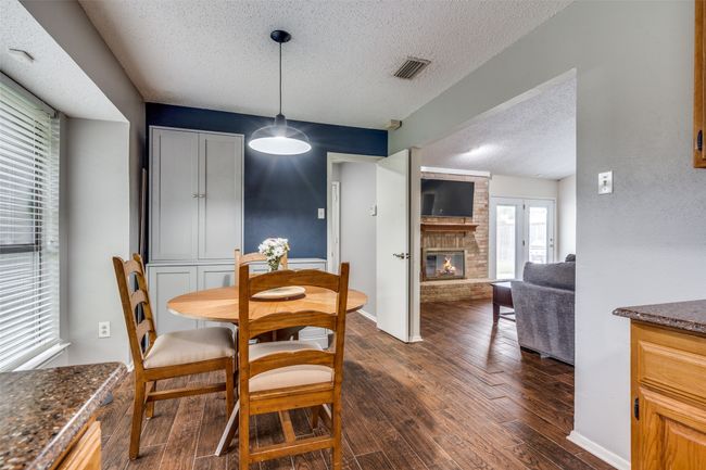 Dining area featuring a textured ceiling, a brick fireplace, and dark wood-style floors | Image 11