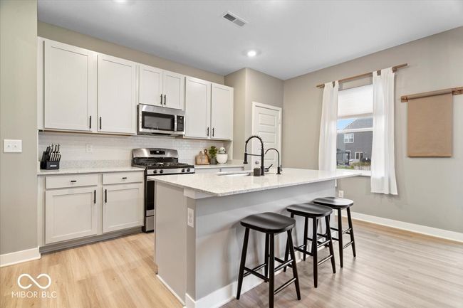 kitchen featuring stainless steel appliances, light wood finished floors, backsplash, a kitchen breakfast bar, and recessed lighting | Image 11