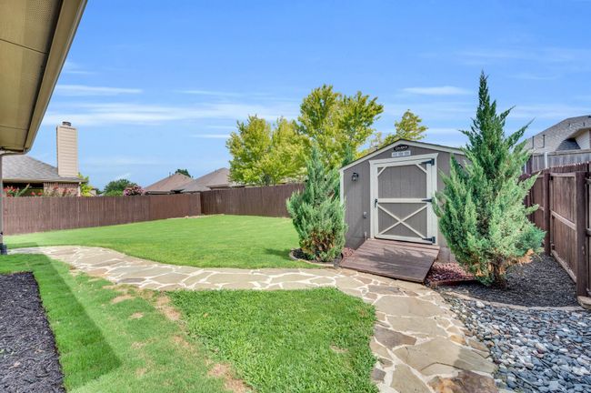 Fenced backyard featuring professionally installed pathway and storage workshop with electrical. | Image 31