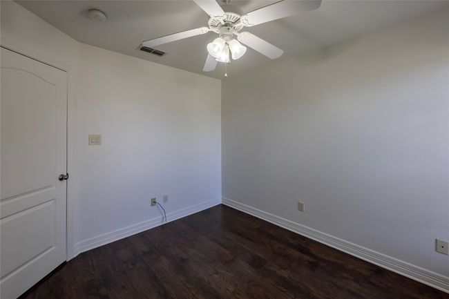 Empty room with baseboards, visible vents, dark wood-type flooring, and ceiling fan | Image 31