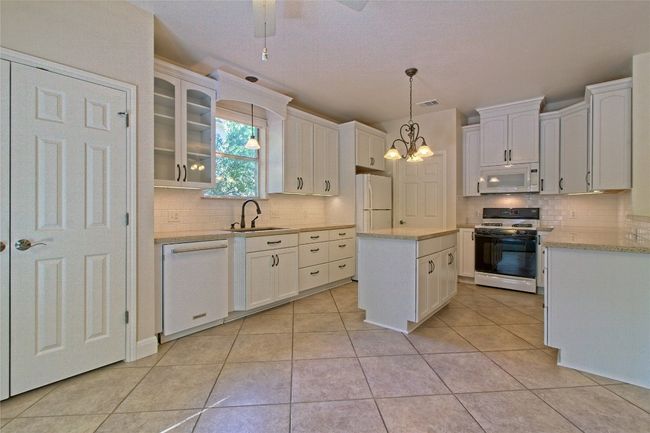 Kitchen with white appliances, backsplash, and white cabinets | Image 14