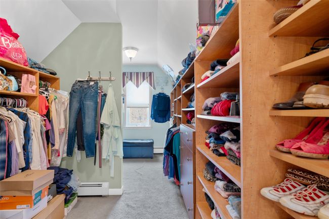 Spacious closet featuring a baseboard radiator, vaulted ceiling, and carpet flooring | Image 19