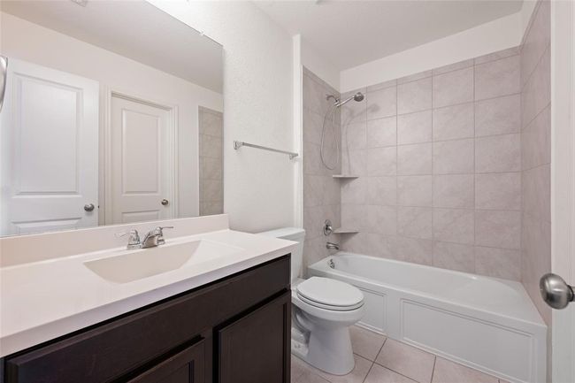 Bathroom featuring toilet, tile patterned flooring, vanity, and shower / bath combination | Image 23