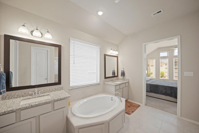 The primary bathroom features dual sinks, large window, tile floors, separate tub, and a walk-in shower with tile surround. | Image 22
