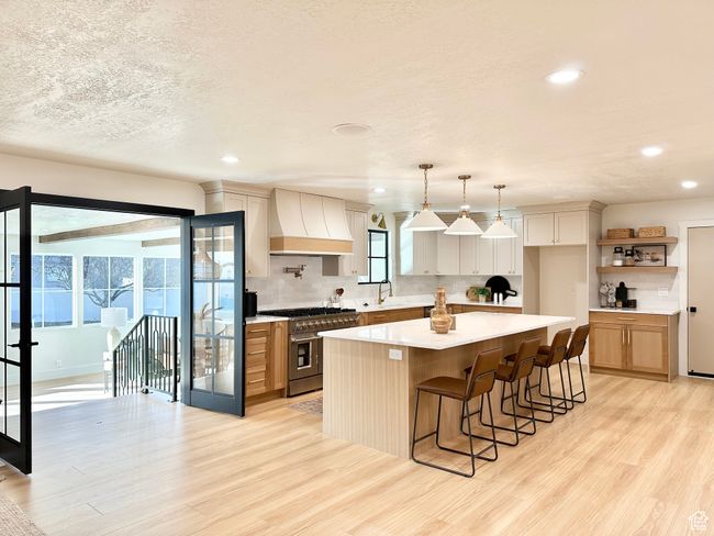 Kitchen with double oven range, custom range hood, light wood-type flooring, light countertops, and recessed lighting | Image 10