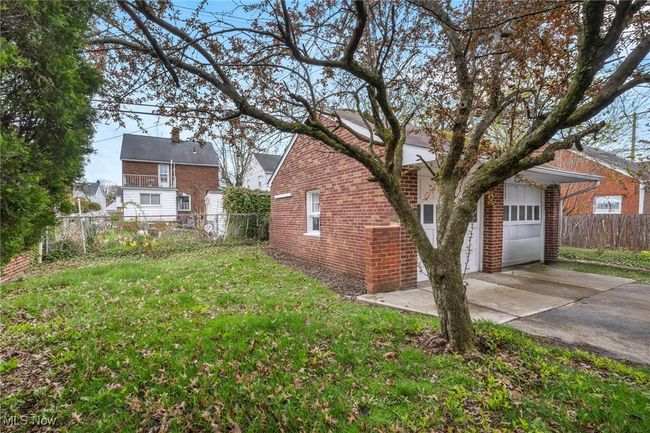 View of property exterior with concrete driveway, fence, a yard, and brick siding | Image 50
