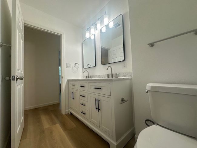 Bathroom with wood finished floors, double vanity, toilet, and baseboards | Image 19