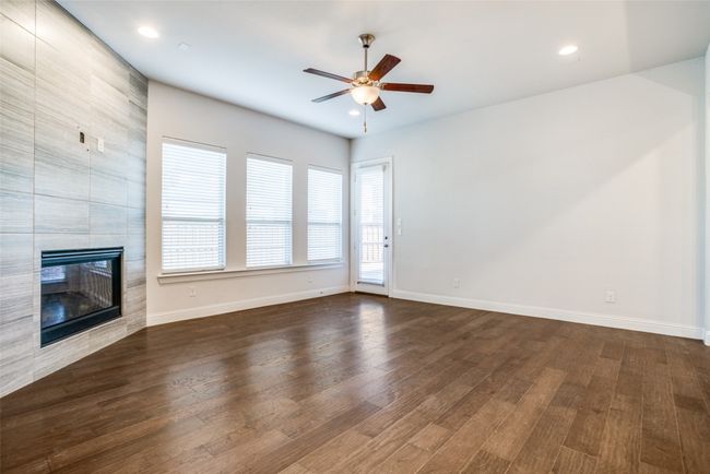 Unfurnished living room with dark wood finished floors, a fireplace, a ceiling fan, and recessed lighting | Image 6