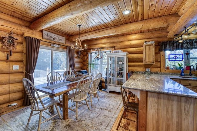 Dining space featuring an inviting chandelier, light wood-style flooring, wood ceiling, beamed ceiling, and rustic walls | Image 17
