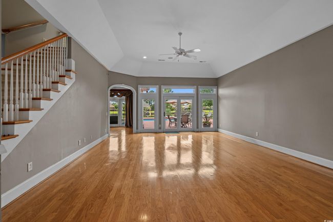 Unfurnished living room featuring ceiling fan, wood finished floors, arched walkways, stairway, and high vaulted ceiling | Image 8