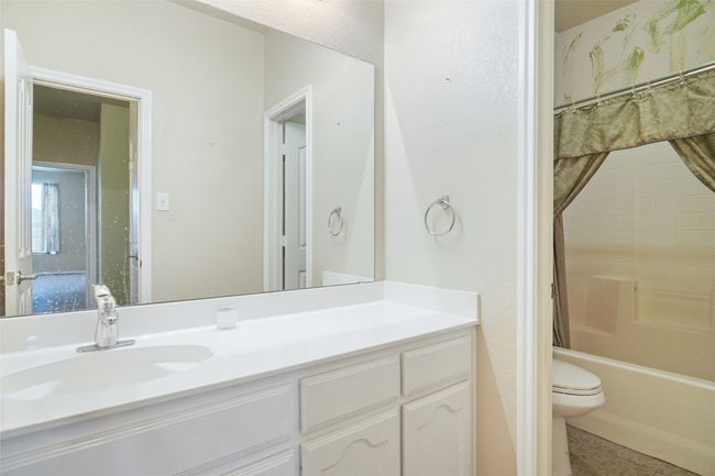 Full bathroom featuring shower / bath combination with curtain, toilet, vanity, and tile patterned floors | Image 23