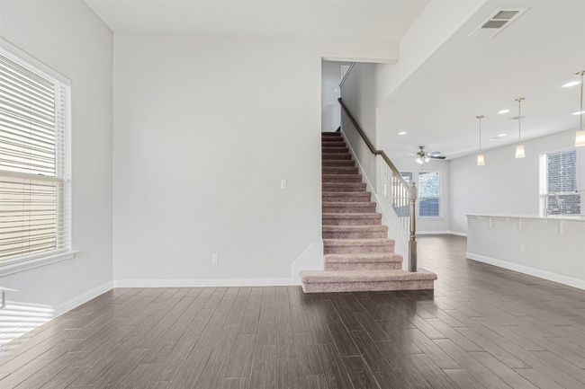 Unfurnished living room featuring dark wood-type flooring, stairs, a ceiling fan, and recessed lighting | Image 24