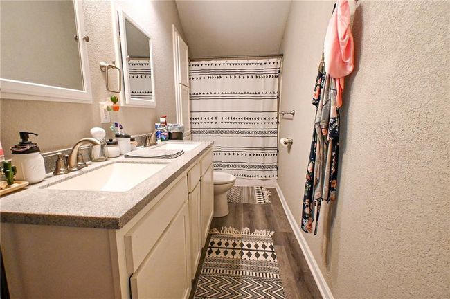 Full bathroom featuring toilet, wood finished floors, vanity, baseboards, and a textured wall | Image 29