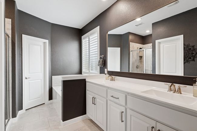 Bathroom featuring a textured wall, a shower stall, a garden tub, double vanity, and tile patterned floors | Image 16