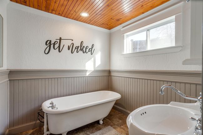 Full bathroom featuring a wainscoted wall, a soaking tub, crown molding, a sink, and wood ceiling | Image 28