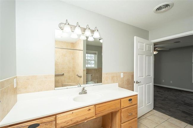 Full bathroom with visible vents, a ceiling fan, a tile shower, tile walls, and tile patterned flooring | Image 27