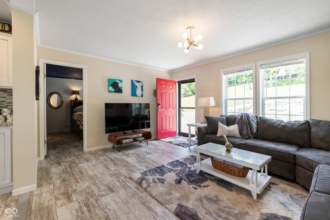 living area with ornamental molding, light wood finished floors, a chandelier, and baseboards | Image 5