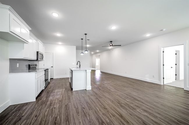 Kitchen featuring light countertops, a sink, a ceiling fan, stainless steel appliances, and dark wood-type flooring | Image 11