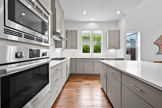 Kitchen with gray cabinetry, stainless steel appliances, light wood-style floors, backsplash, and recessed lighting | Image 9