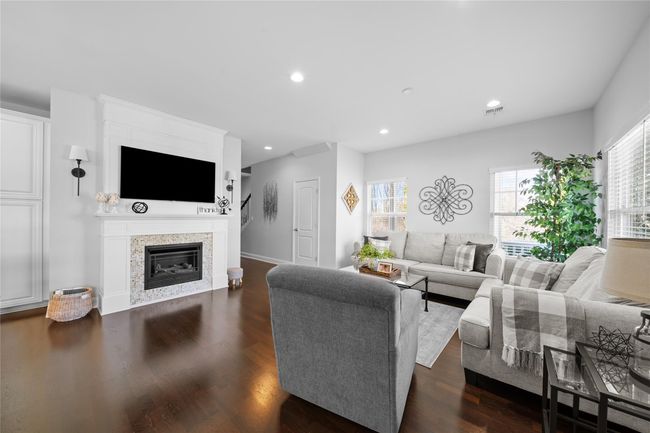 Living area featuring visible vents, baseboards, recessed lighting, dark wood-type flooring, and a glass covered fireplace | Image 9