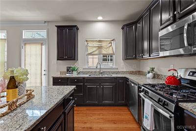 Kitchen with sink, light hardwood / wood-style floors, light stone counters, and stainless steel appliances | Image 3