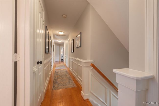 Hallway featuring visible vents, a decorative wall, an upstairs landing, light wood finished floors, and a wainscoted wall | Image 30