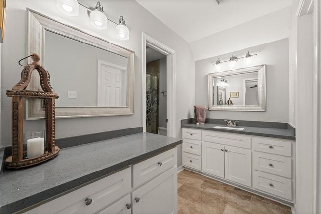 Bathroom features a modern design with dual sinks, sleek gray countertops, and ample white cabinetry. | Image 28