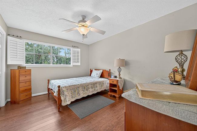 This inviting bedroom features a wide window, ceiling fan, and rich flooring. It offers flexibility—whether used for rest, study, or guests. | Image 29