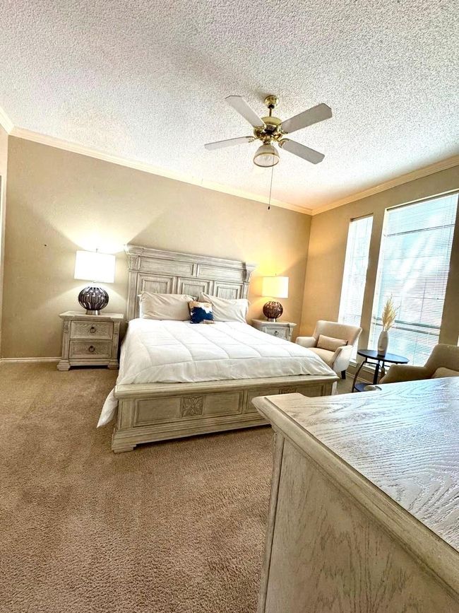 Bedroom featuring crown molding, light colored carpet, and a textured ceiling | Image 12