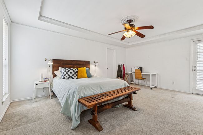 Carpeted bedroom with a tray ceiling, ornamental molding, access to exterior, baseboards, and ceiling fan | Image 12