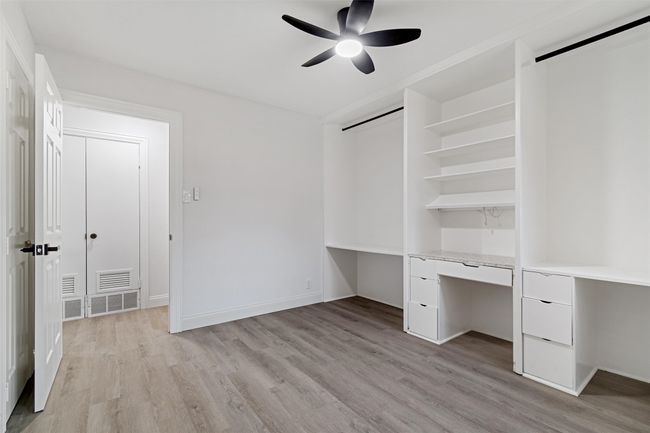 Unfurnished bedroom featuring ceiling fan, light wood-type flooring, and built in desk | Image 31