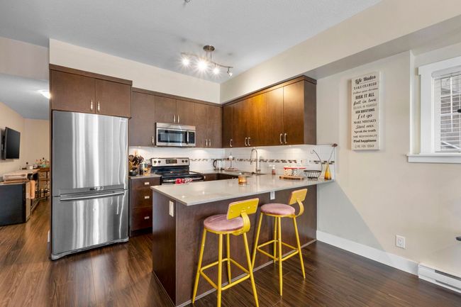 Kitchen with a baseboard radiator, dark wood-type flooring, stainless steel appliances, and a peninsula | Image 8