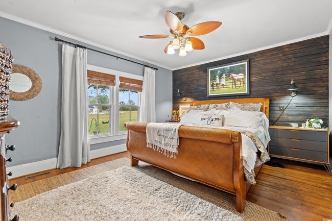Bedroom with ornamental molding, wood finished floors, wood walls, and ceiling fan | Image 16